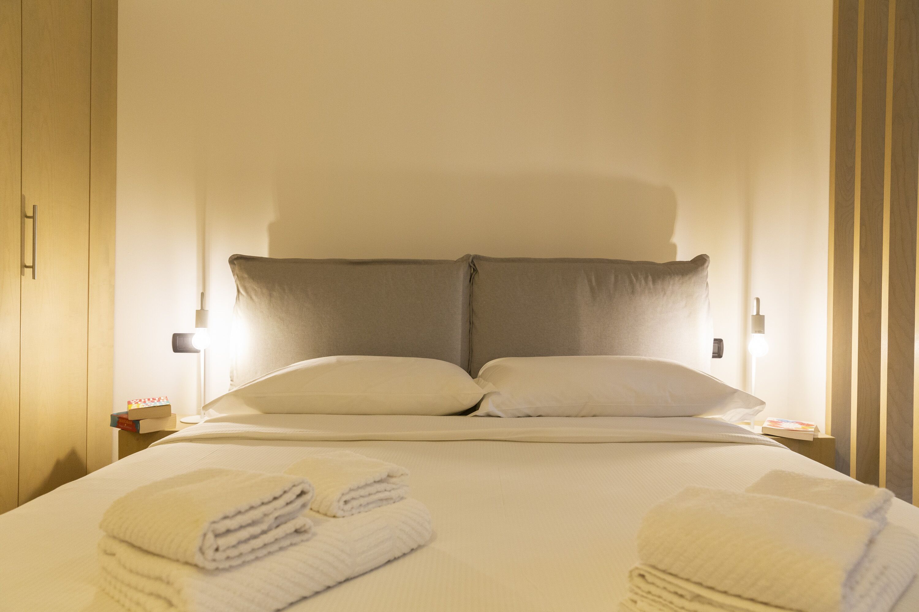 A neatly made bed with two pillows and folded towels on the bed.