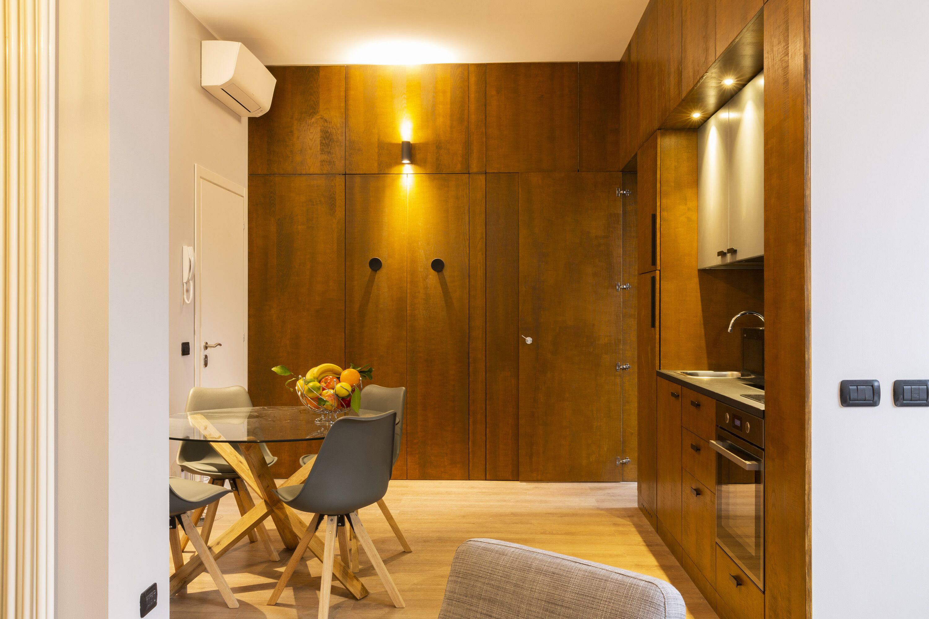 Une cuisine compacte avec des meubles en bois, une table à manger en verre et un robinet moderne.