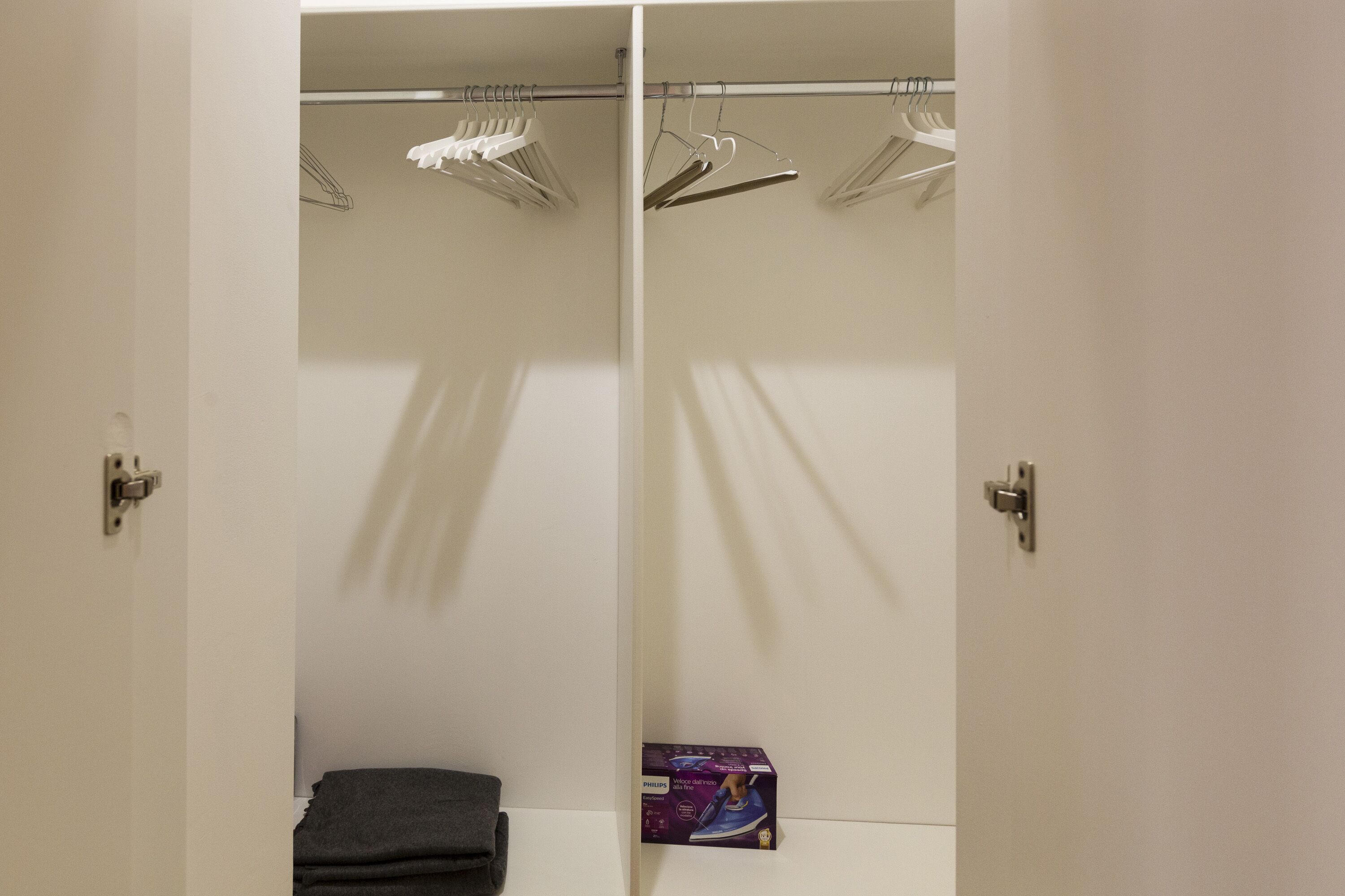 A walk-in closet with a hanging rod and a folded towel on the floor.