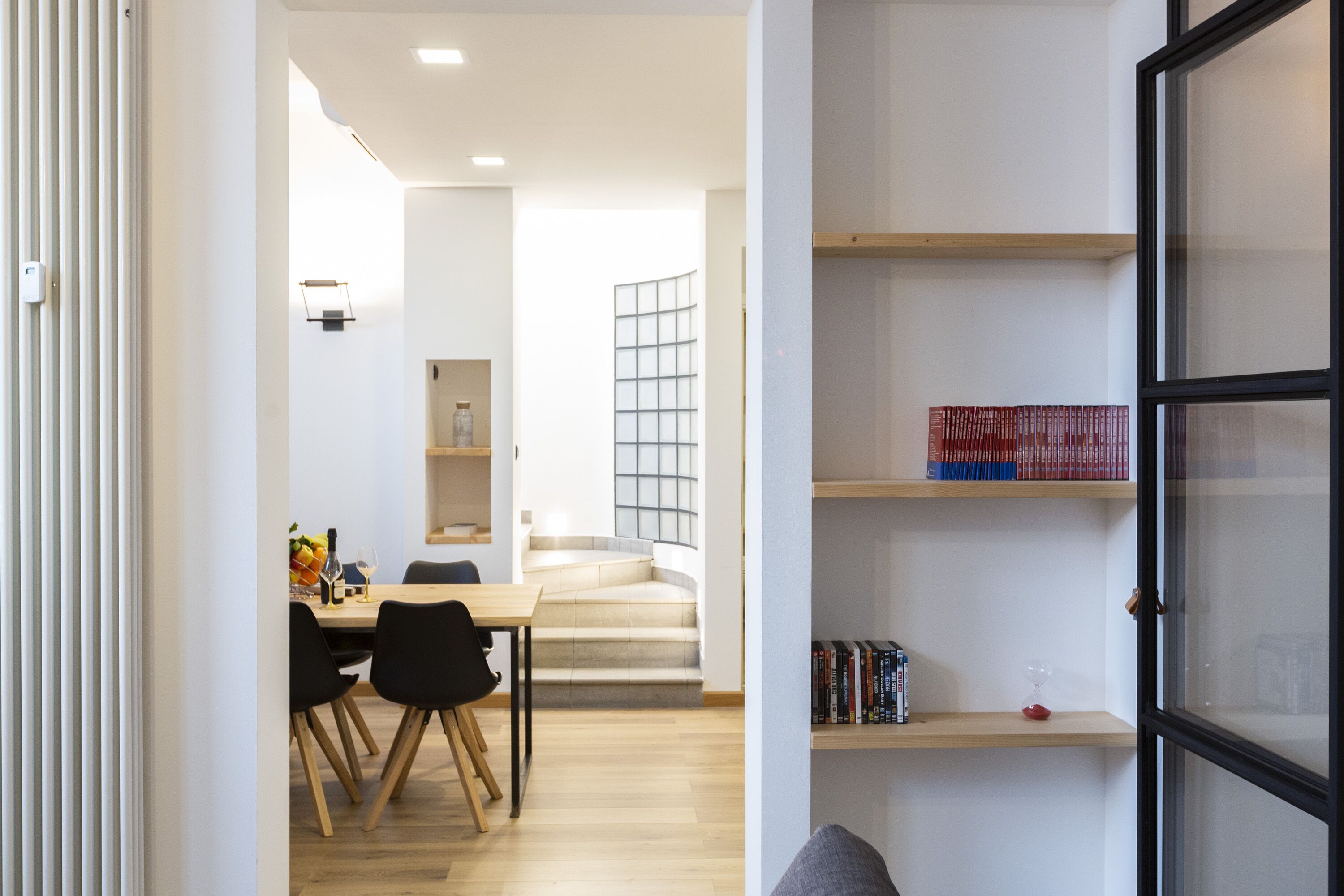 Un intérieur moderne comprenant un coin repas, un escalier et des étagères.