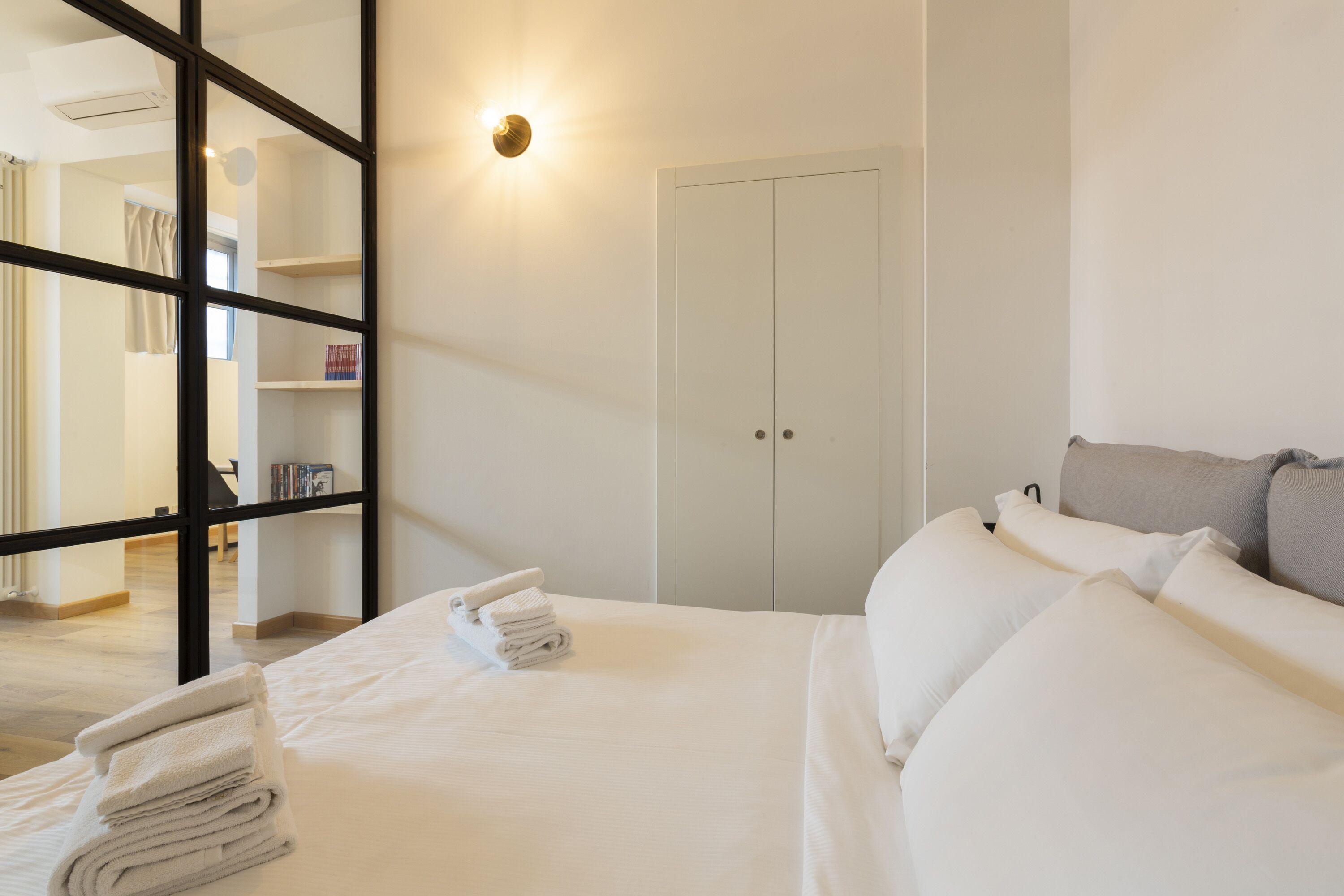 A hotel room with a bed, a wardrobe, and a mirror.