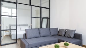Una sala de estar moderna con un sofá gris, una mesa de centro de madera y dos plantas en macetas.