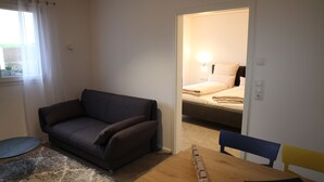 Ein Zimmer mit einer Couch, einem kleinen runden Tisch und einem Holztisch mit Stühlen.