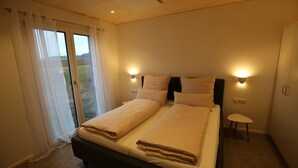 Ein Schlafzimmer mit einem Bett, zwei Nachttischen und einem fenster mit Vorhängen.