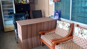 A bar area with a wooden counter, a refrigerator stocked with beverages, and a seating area with patterned cushions. - Teley Lodge (Accra)
