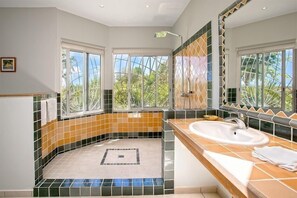 A bathroom with a large window, a bathtub, and a sink.