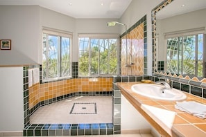 A bathroom with a large window, a bathtub, and a sink.