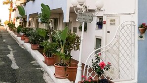 Un hotel con varios balcones, macetas con plantas y un cartel que indica que es un hotel.