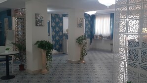 Una habitación con suelo de baldosas, una silla blanca, una mesita y plantas en macetas.