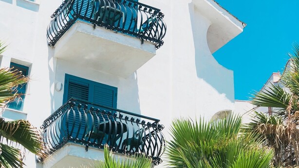 Un edificio blanco con contraventanas azules y balcones negros.