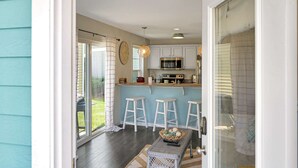 A kitchen with white cabinets, a microwave, and a dining area with white stools. - Star Gaze on your Private Second Level Deck! (Ottawa)