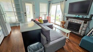 Una sala de estar con sofá, televisor, chimenea y ventana con persianas.