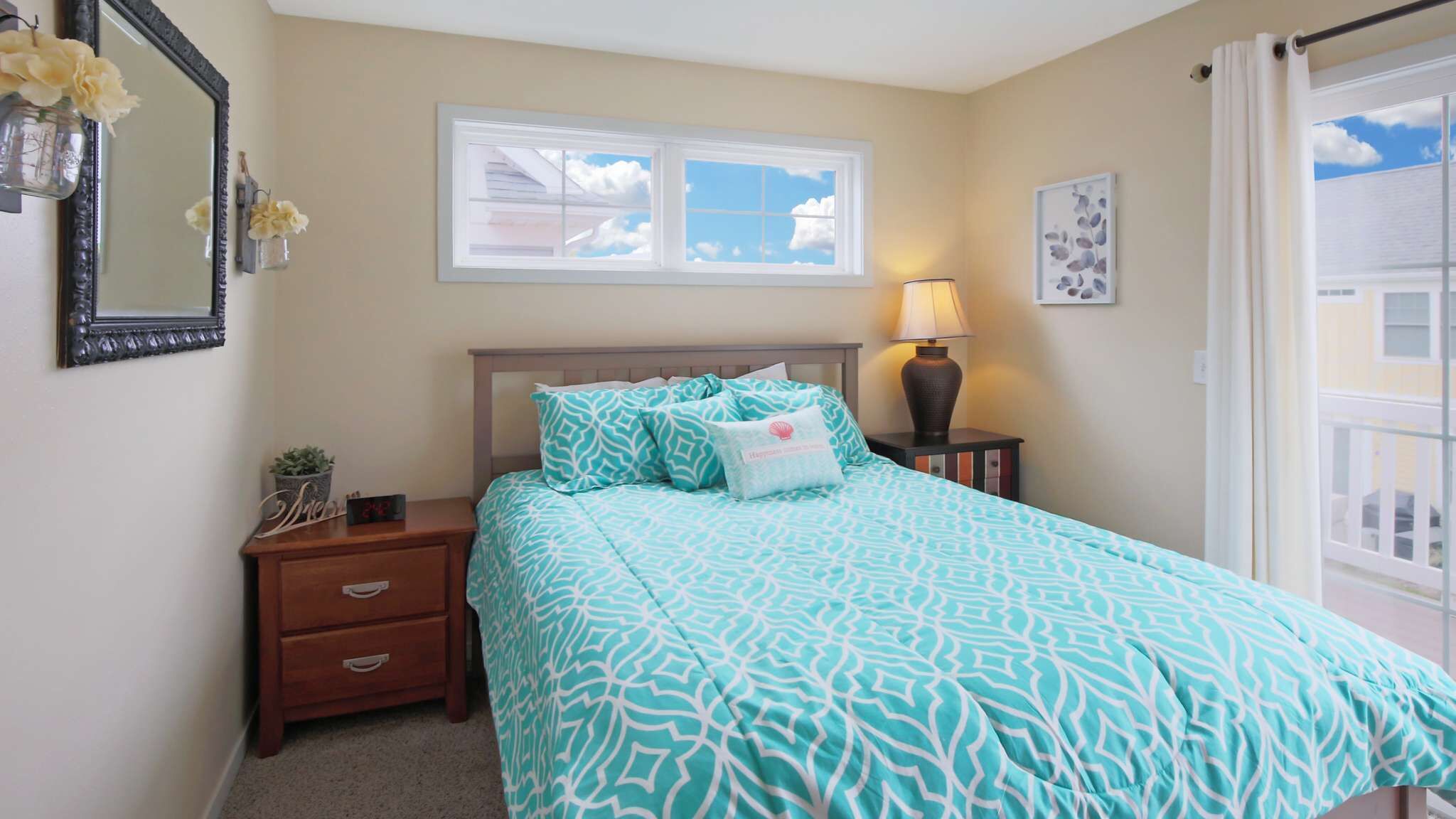 A bedroom with a bed, nightstand, lamp, and a window with a view.