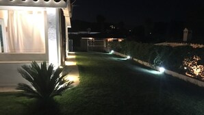 Een nachtzicht van een verlicht pad dat naar een gebouw met een overdekte ingang leidt.