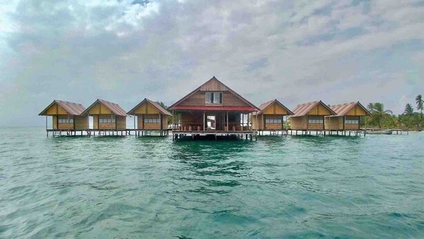 A series of overwater bungalows with a central building and individual rooms, connected by walkways over water. -  Paradise Over the Water Cabins in San Blas (Narganá)
