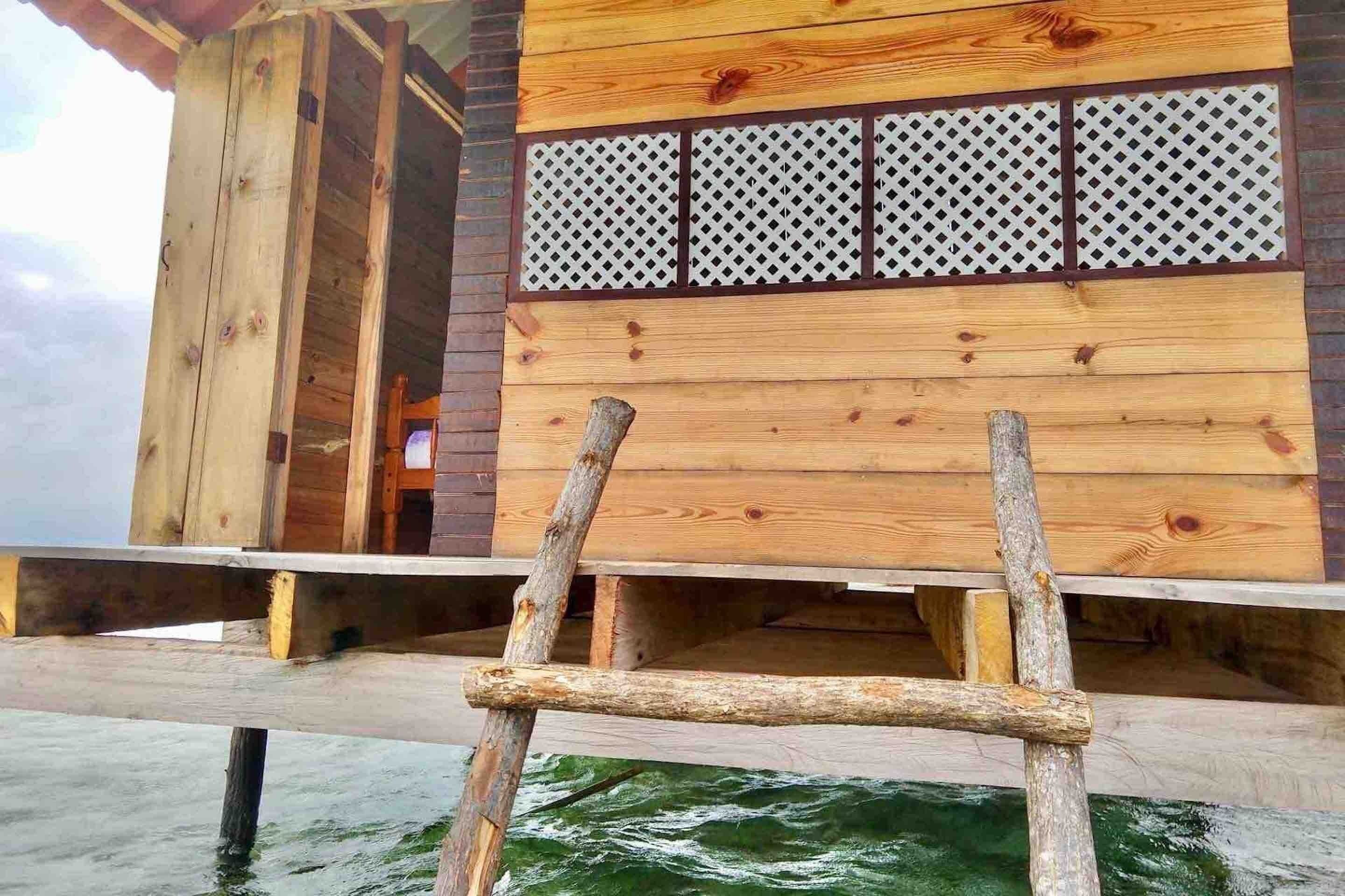 A wooden structure with a ladder leading to a platform over water.