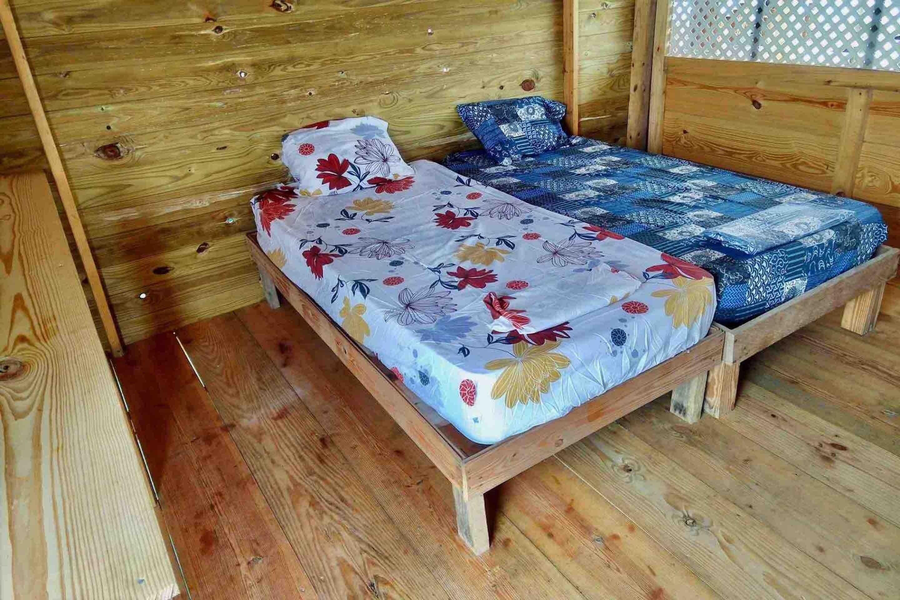 A wooden bed with floral bedding in a cabin-style room.