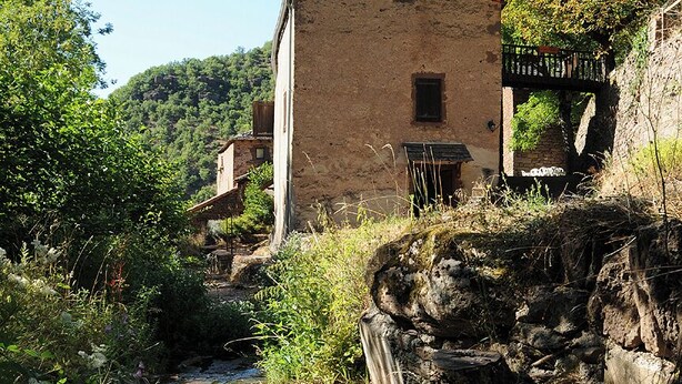 Un bâtiment rustique en pierre, doté d’un toit en pente, situé au bord d’un étroit canal.