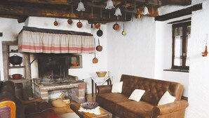 Un salon de style rustique avec une cheminée, des meubles en cuir et des pots suspendus.