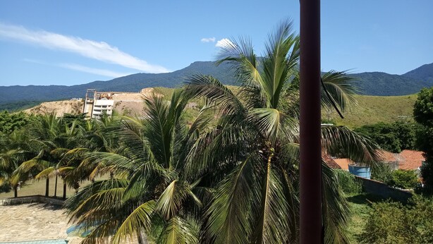A view of a beach with palm trees and a mountain in the background. - Hotel Jota (São Sebastião)