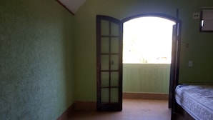 A room with a bed, a door leading to a balcony, and a tiled floor. - Hotel Jota (São Sebastião)