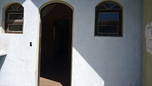 A building with a white exterior, a central arched doorway, and two arched windows on either side. - Hotel Jota (São Sebastião)