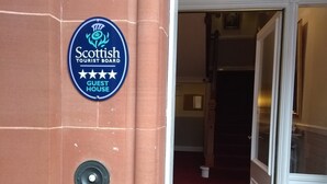 A hotel entrance with a blue sign indicating it is a guest house. - Lindean Guest House (Dumfries)