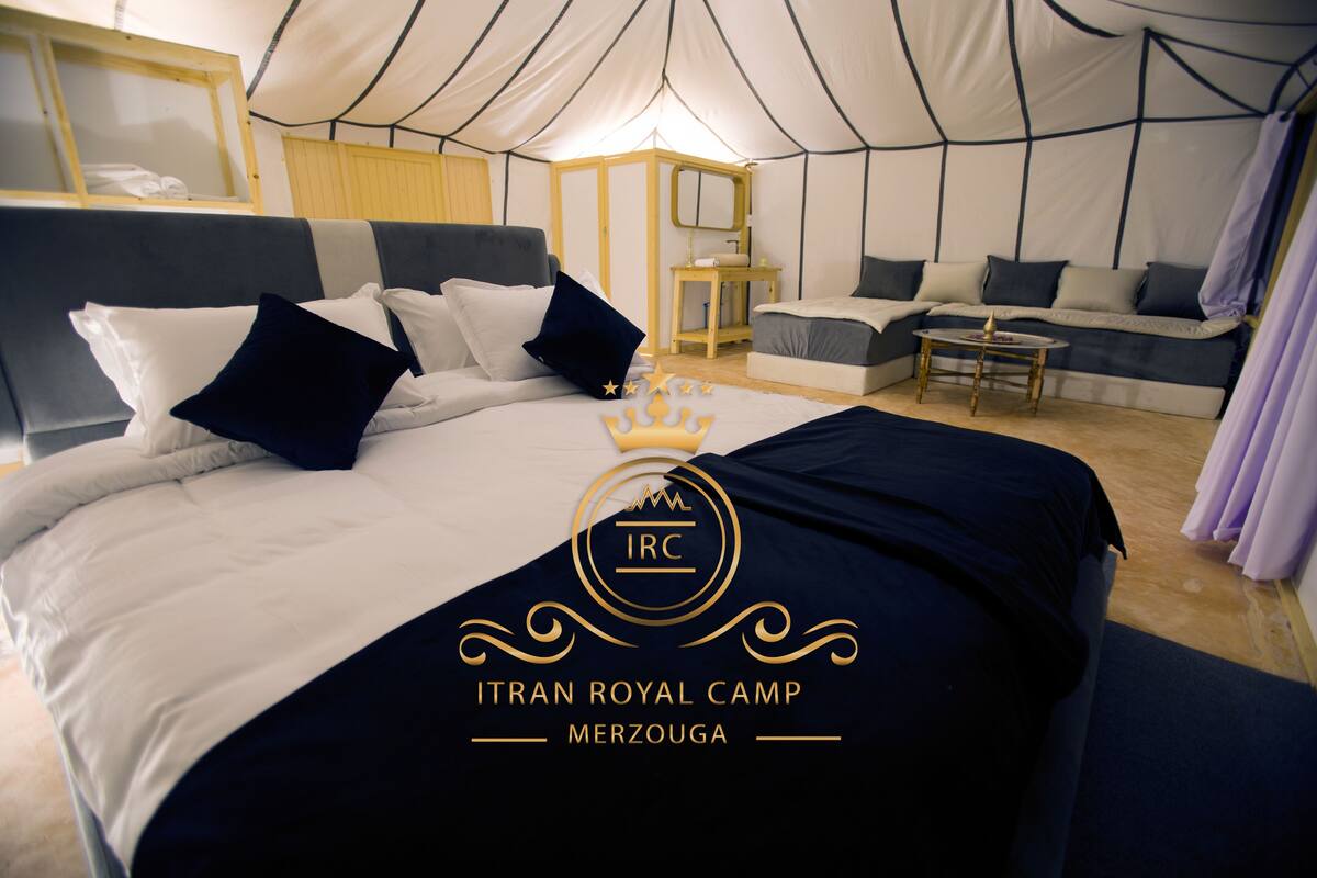 A tented room with a bed, a sofa, and a small table.