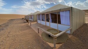 A desert tent with a covered walkway and a woven basket. - Itran Royal Camp (Taouz)