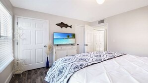 A bedroom with a bed, a TV, a fish decoration, and a door.