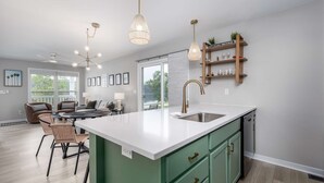 Una cocina moderna con una isla grande, iluminación colgante y vistas al exterior.