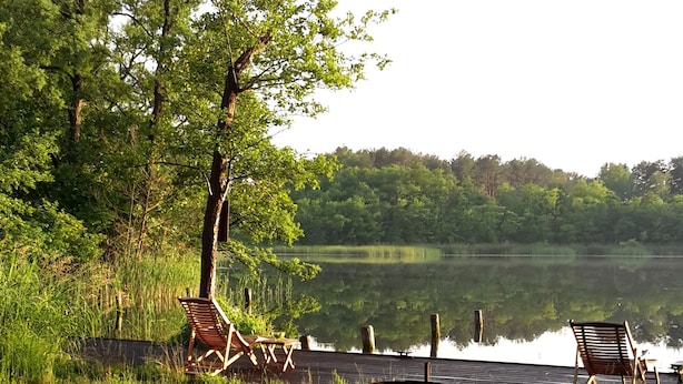 Un cadre idyllique au bord du lac, avec une jetée en bois, deux chaises en bois et un barbecue.