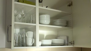 Une cuisine avec des meubles blancs, un évier en acier inoxydable, une bouilloire et un grille-pain.
