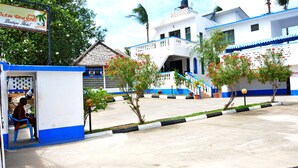 Un hotel con fachada azul y blanca, una estructura de techo de paja y un cartel anunciando Ocean View Nyali Boutique Hotel.
