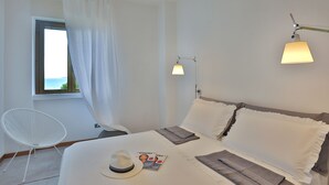 Una camera da letto ordinata con un letto, una lampada da comodino, una sedia e una finestra con tende.