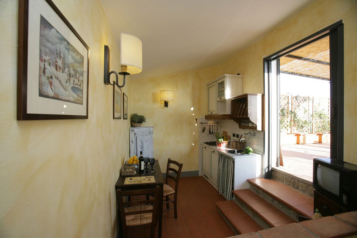 A compact kitchen with a dining area, a TV, and a window with a view of the outside.