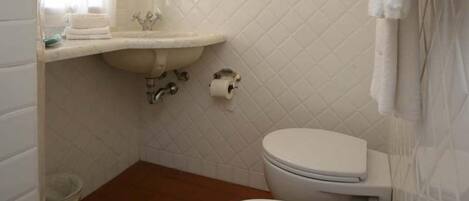 Une salle de bain équipée d’un lavabo, d’un miroir, de toilettes et d’un bidet.
