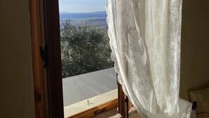 Une fenêtre donnant sur un paysage lointain, un radiateur en dessous et un cadre de porte en bois.