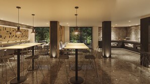 A modern dining area with high tables and chairs, pendant lighting, and a view of greenery through large windows. - Senator Cala Millor Hotel (Son Servera)
