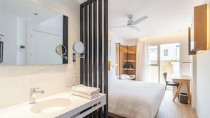 A modern hotel room with a large bed, a separate desk area, a bathroom with a large mirror and two round mirrors, and a ceiling fan. - Senator Cala Millor Hotel (Son Servera)