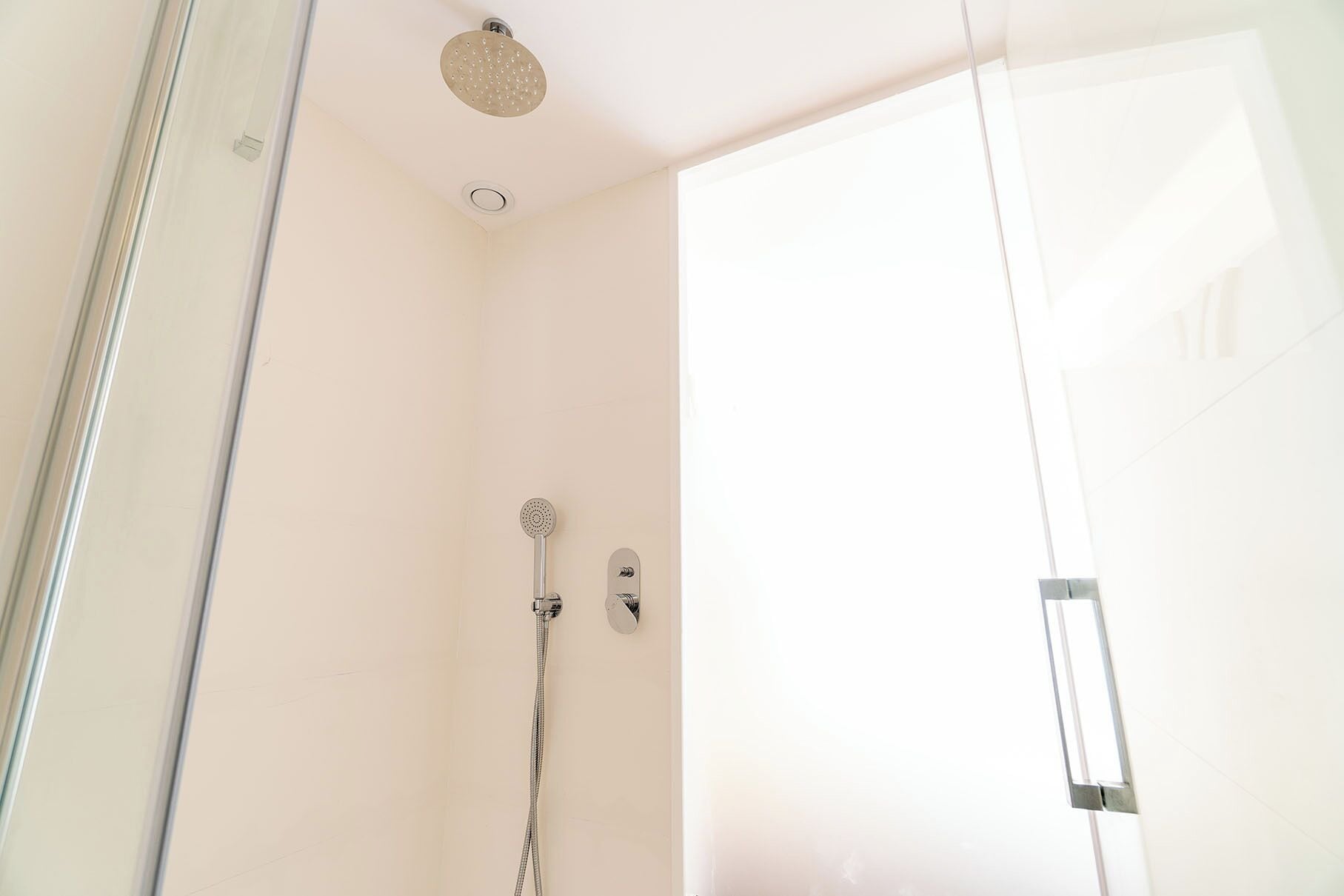 A shower with a handheld showerhead and a wall-mounted faucet.