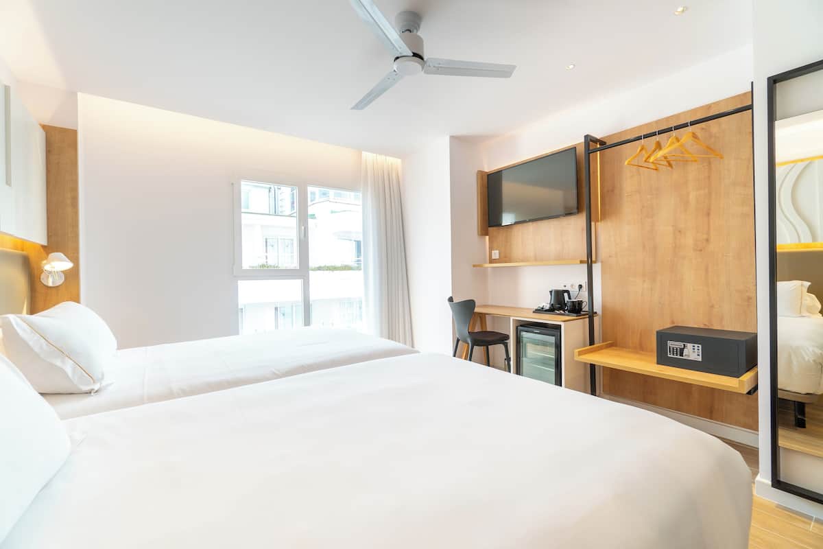 A hotel room with two beds, a desk, a TV, and a wardrobe.