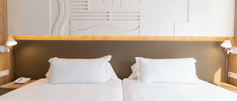 A hotel room with a double bed, a wooden headboard, and a wall-mounted light fixture.