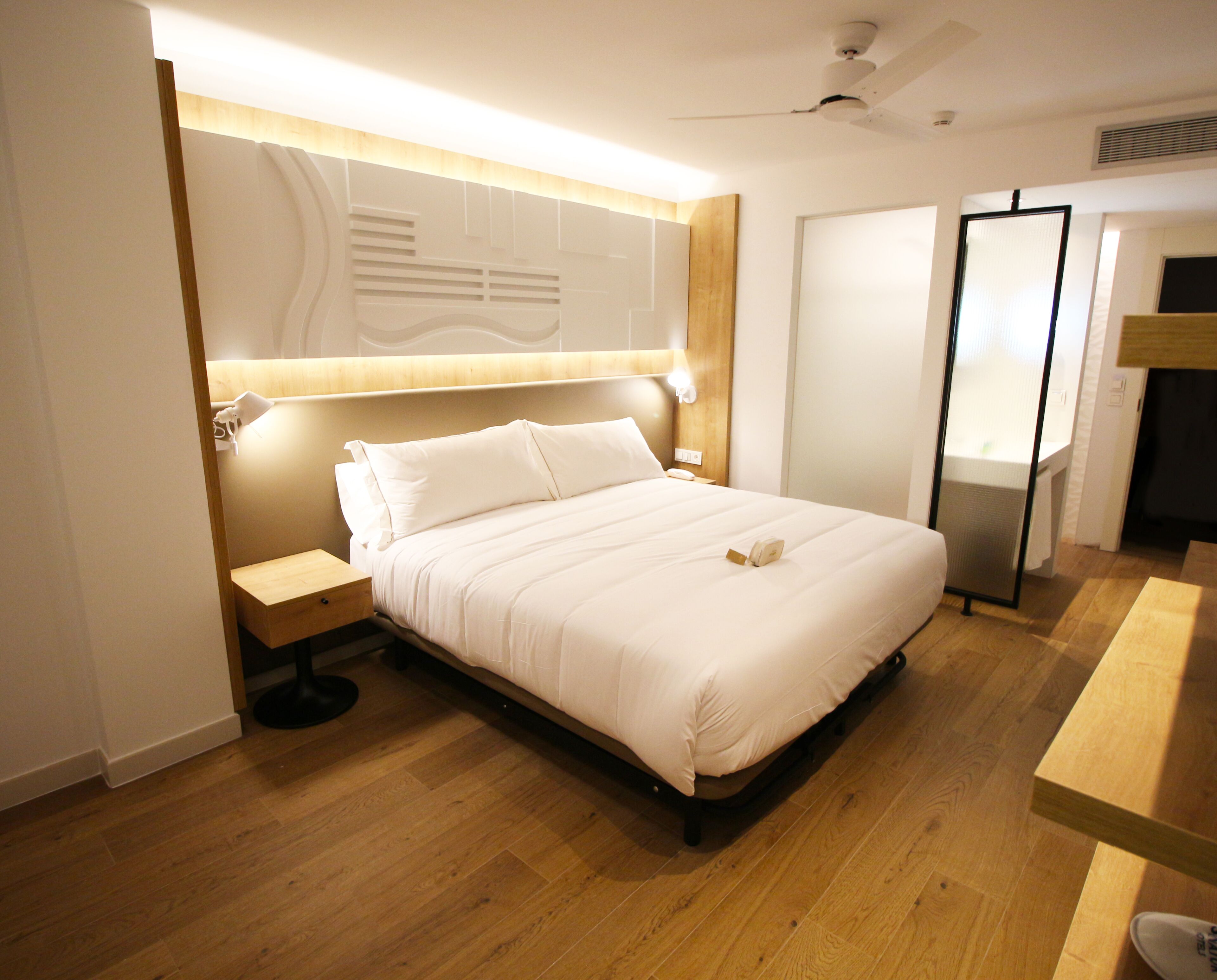 Una habitación de hotel con una cama grande, una mesita de noche, un escritorio y un armario.