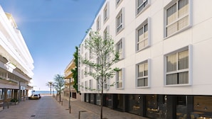 A modern hotel with a clean facade, multiple floors, and a tree in front. - Senator Cala Millor Hotel (Son Servera)