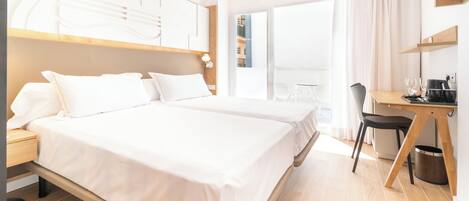 A modern hotel room with a large bed, a desk, and a view of the city.