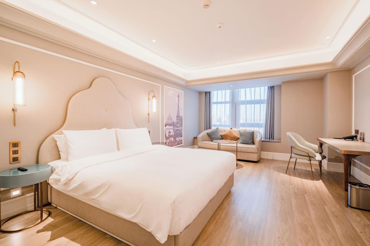 Una habitación de hotel moderna con una cama grande, un escritorio, un sofá y un comedor.