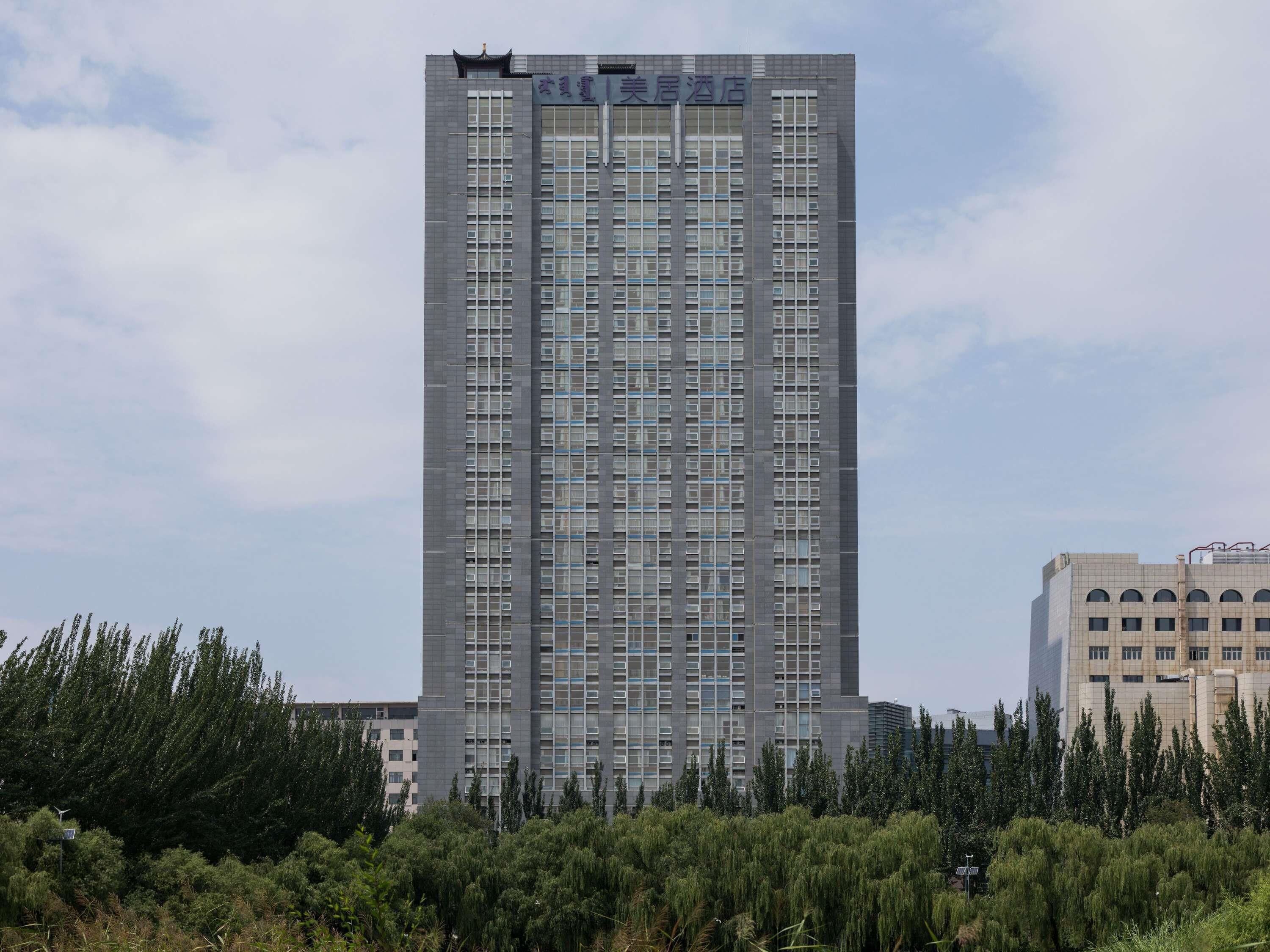 A tall, modern building with a grid of windows and a sign at the top.