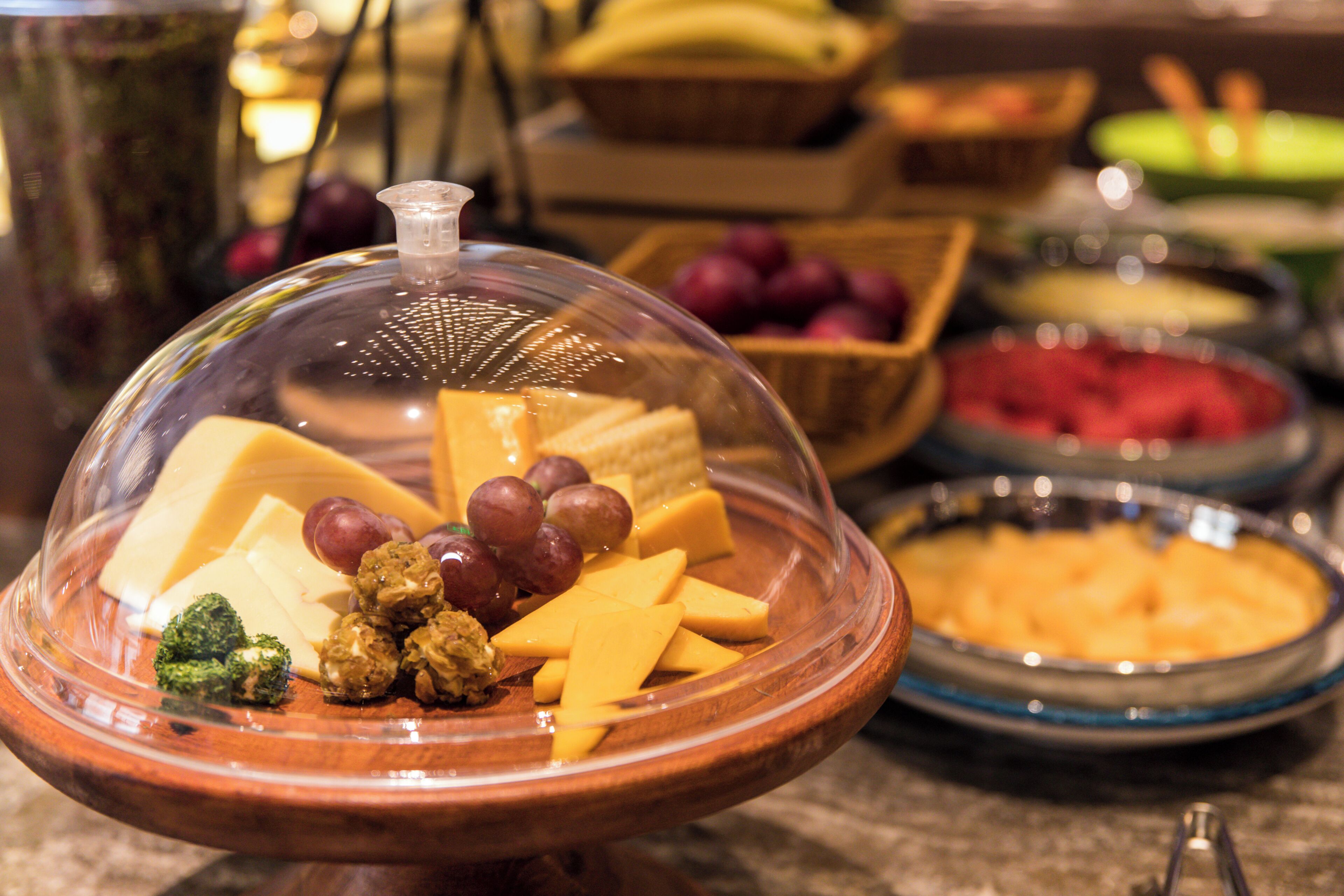 Une présentation de produits alimentaires comprenant une variété de fromages, de raisins et de noix.
