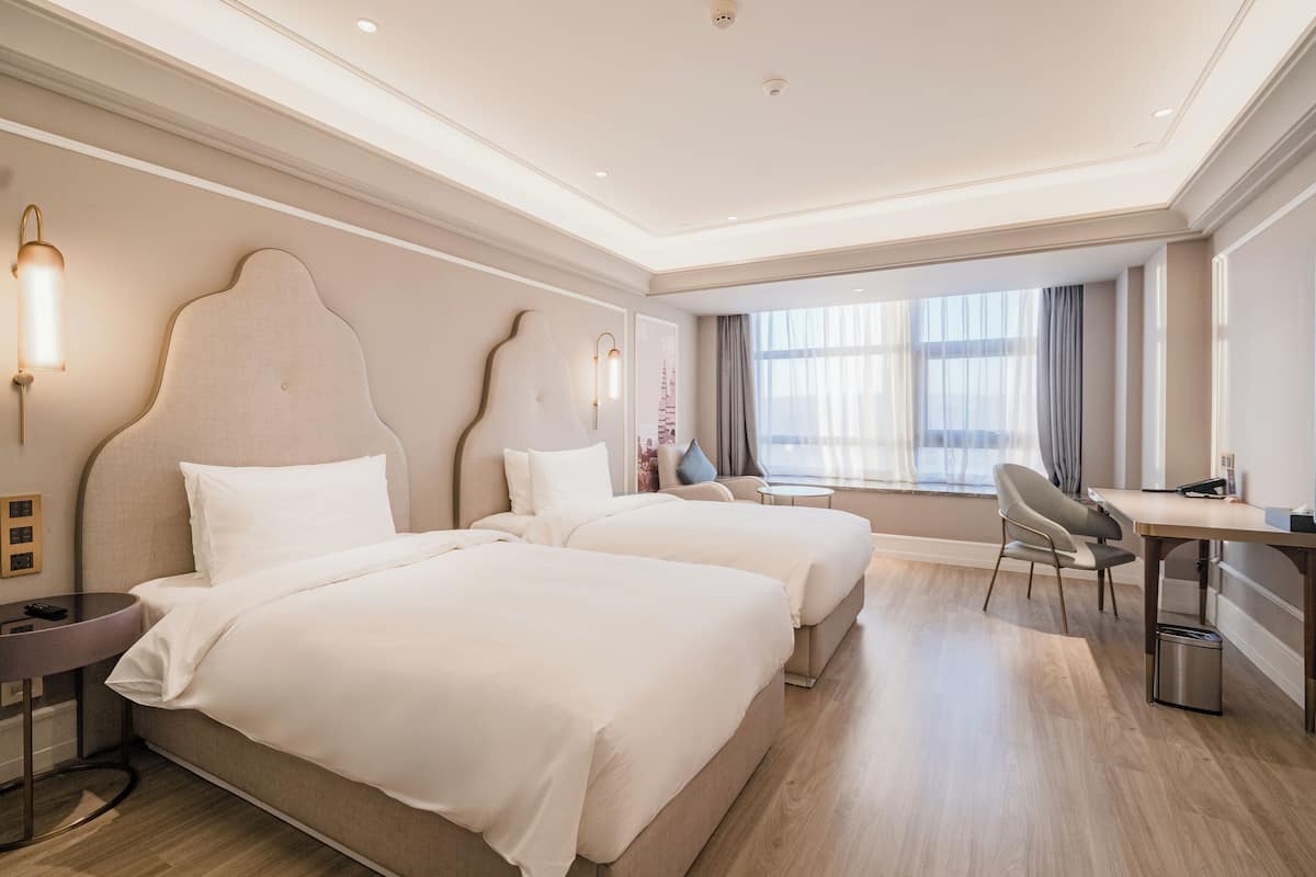 Habitación de hotel con dos camas, un escritorio y una silla.